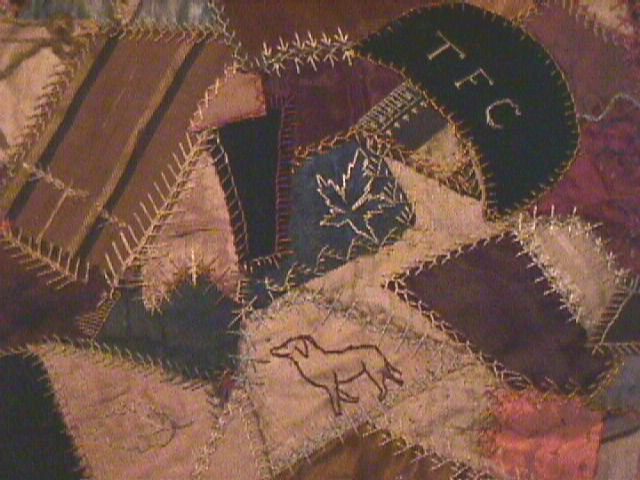Patchwork quilt; wide border of blue velvet; crazy patchwork with heavy stitching; curtain rings along one edge