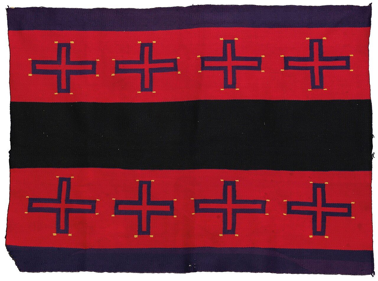 twill-woven in commercial 4-ply wool yarn, in aniline colors, with a woman's shawl design, composed of two rows of Spider Woman crosses flanking a broad central panel. 47 in. by 64 in. Exhibited Saint Louis Art Museum: “Navajo Weavings from the Andy Williams Collection,” October…