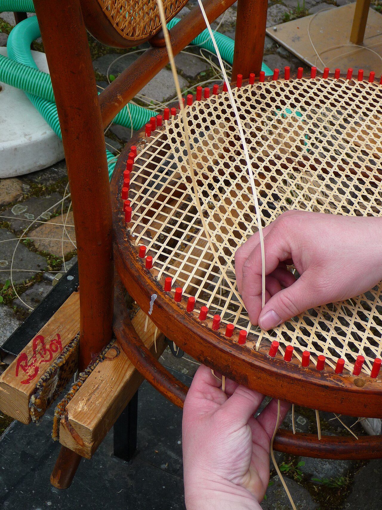Chair caner at work. Cane bottomed bentwood chair.