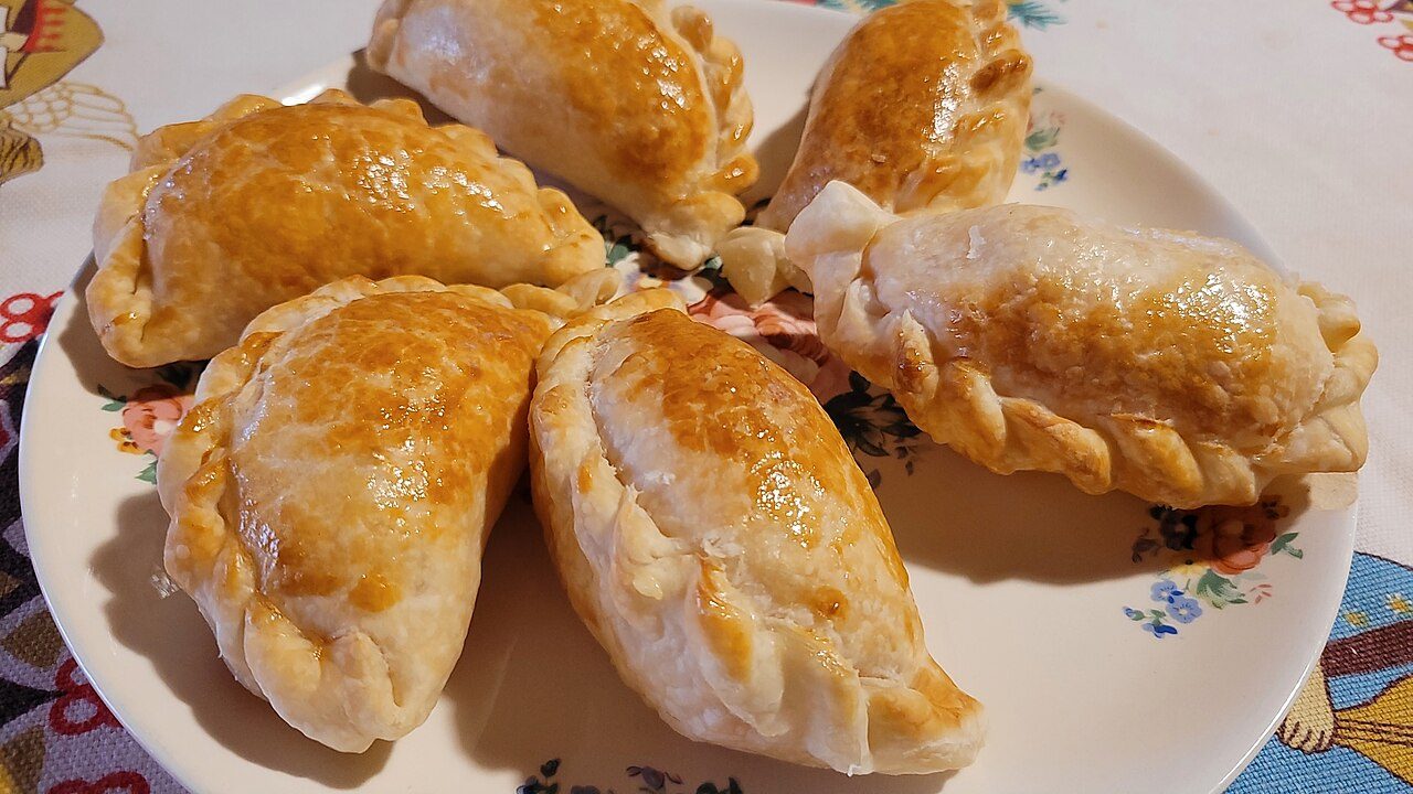 Empanadas argentinas de jamón y queso con orégano y tomate, pinceladas con huevo batido.