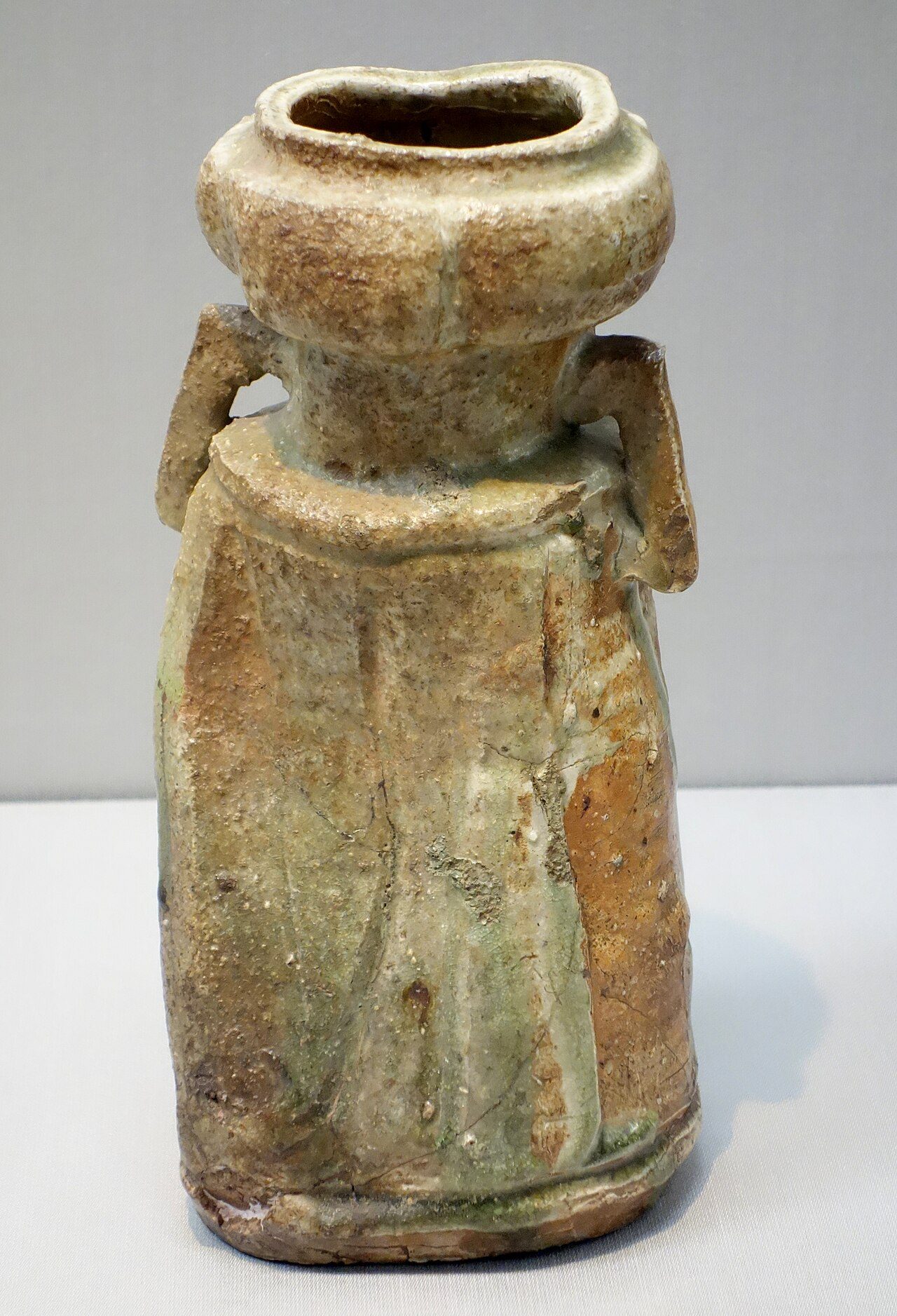 Flower Vase with Lugs, Iga ware, Edo period, 17th century. H. 28.6, mouth D. 8.8x9.1, bottom 11.8x12.7. G5732. Exhibit in the Tokyo National Museum, Tokyo, Japan. This artwork is old enough so that it is in the public domain.