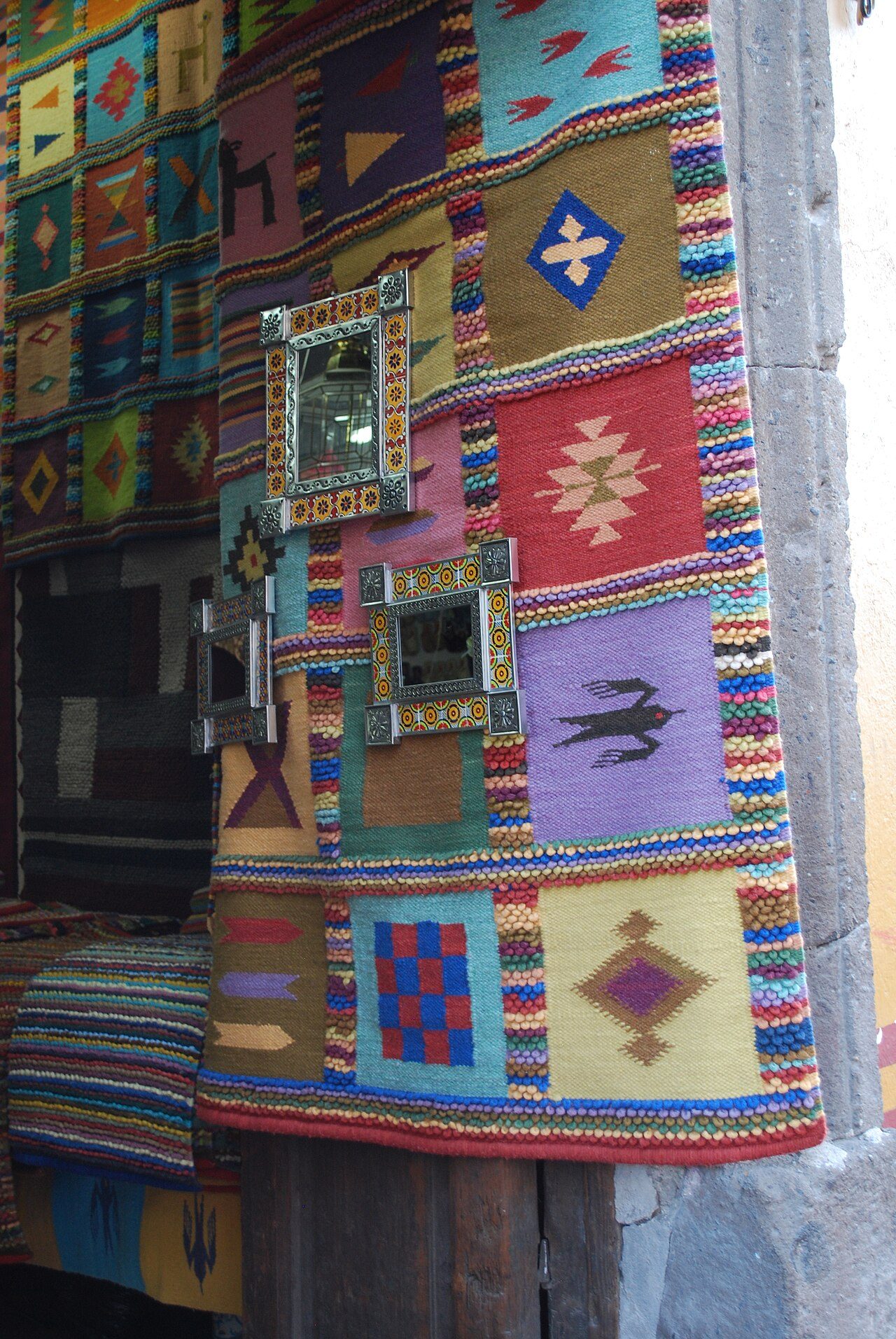 Entrance to a crafts store with rug and mirrors on display. In San Miguel de Allende, Guanajuato, Mexico