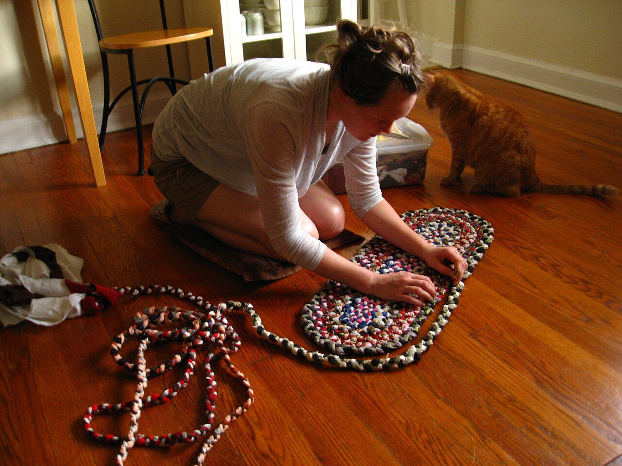 A picture of a woman sewing a New England-style braided rug from scraps of old fabric. Picture was taken with a Canon PowerShot SD850 IS digital ELPH camera.