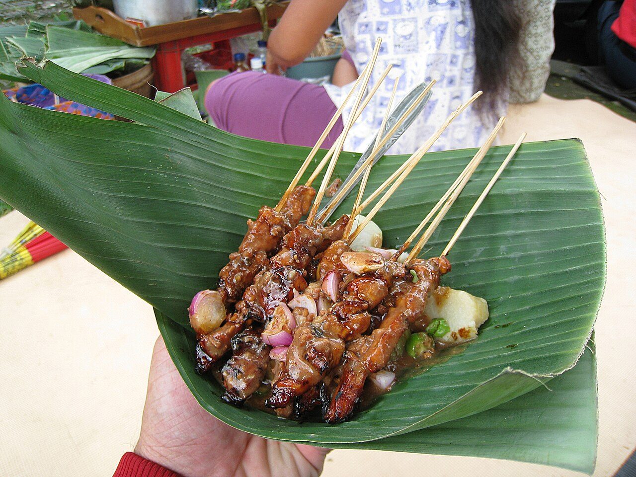 Chicken satay with lontong glutinous rice on banana leaf plate at a humble "kakilima" or road side chicken satay seller near Borobudur, Central Java.