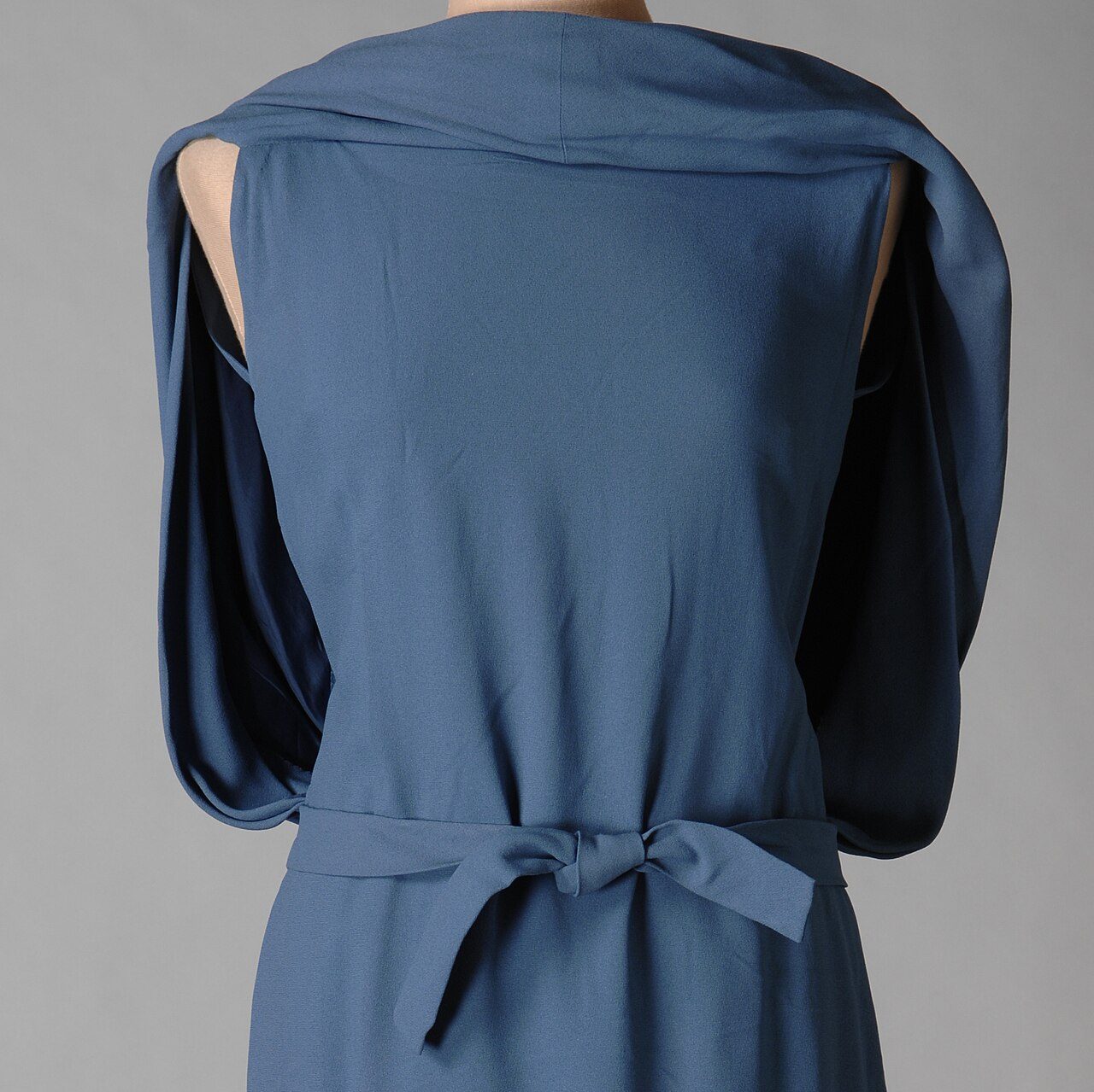 Objectgegevens Titel: Blauwe japon zonder mouw Beschrijving: Blauwe japon zonder mouw, met sjaalkraag tot in de taille verwerkt, rechte rok, gevoerd. Herkomst: St. Historisch Kostuummuseum. Trefwoorden: japon, bovenkleding, vrouwenkleding, kleding, kostuum Datering: 1960 - 1965…