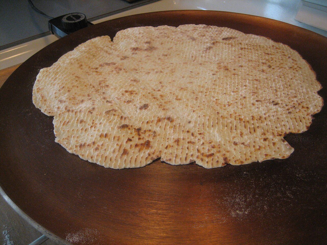 A lefse on a griddle, cooking.
