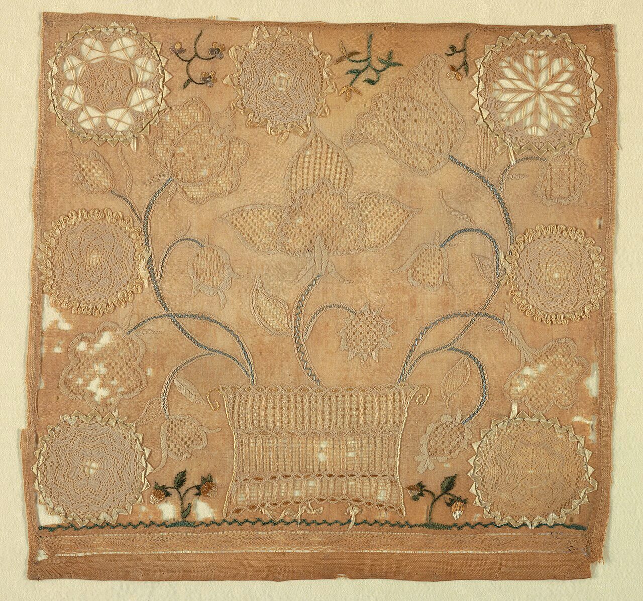 A basket of large flowers, with the flowers executed in drawn work, cut work, and hollie point in white embroidery on a white ground. The basket trimmings, stems of flowers, and isolated sprigs of flowers at bottom are worked in colored silks. With the inscription: Mary Babb…