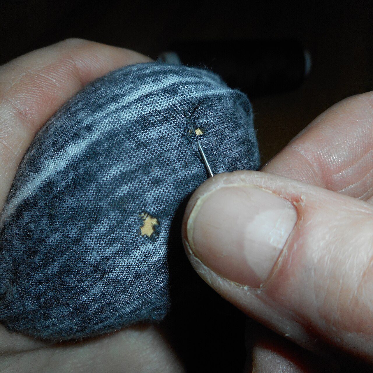 mending hole with darning mushroom, needle and thread