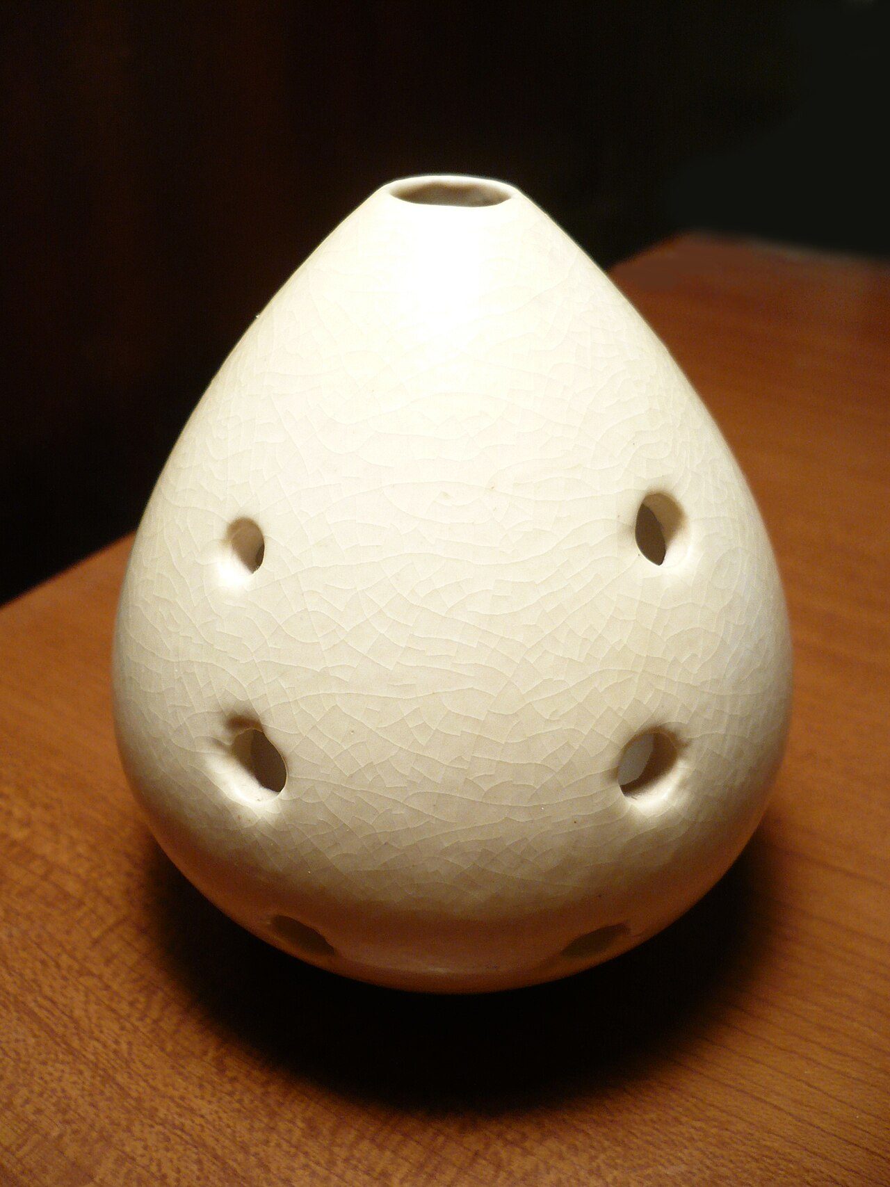 The front of a glazed pottery xun , showing blowing hole and six finger holes.