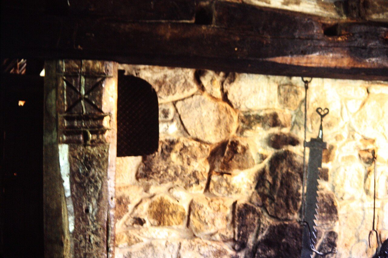 Traditional stone fireplace in northern England. The carved St. Andrew's cross in the left hand wooden post was to prevent witches from flying down the chimney. Witch post, Stang End Cottage, Ryedale Folk Museum, York.