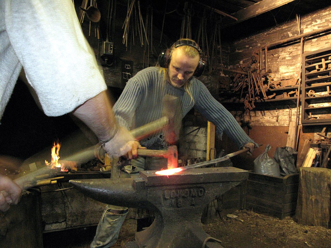 A typical smithy in Finland. Shot during a tourist trip to artist blacksmith Jesse Sipola's smithy next to lake Bodom. Tourist working to aid the smith in smithing by using a sledge.