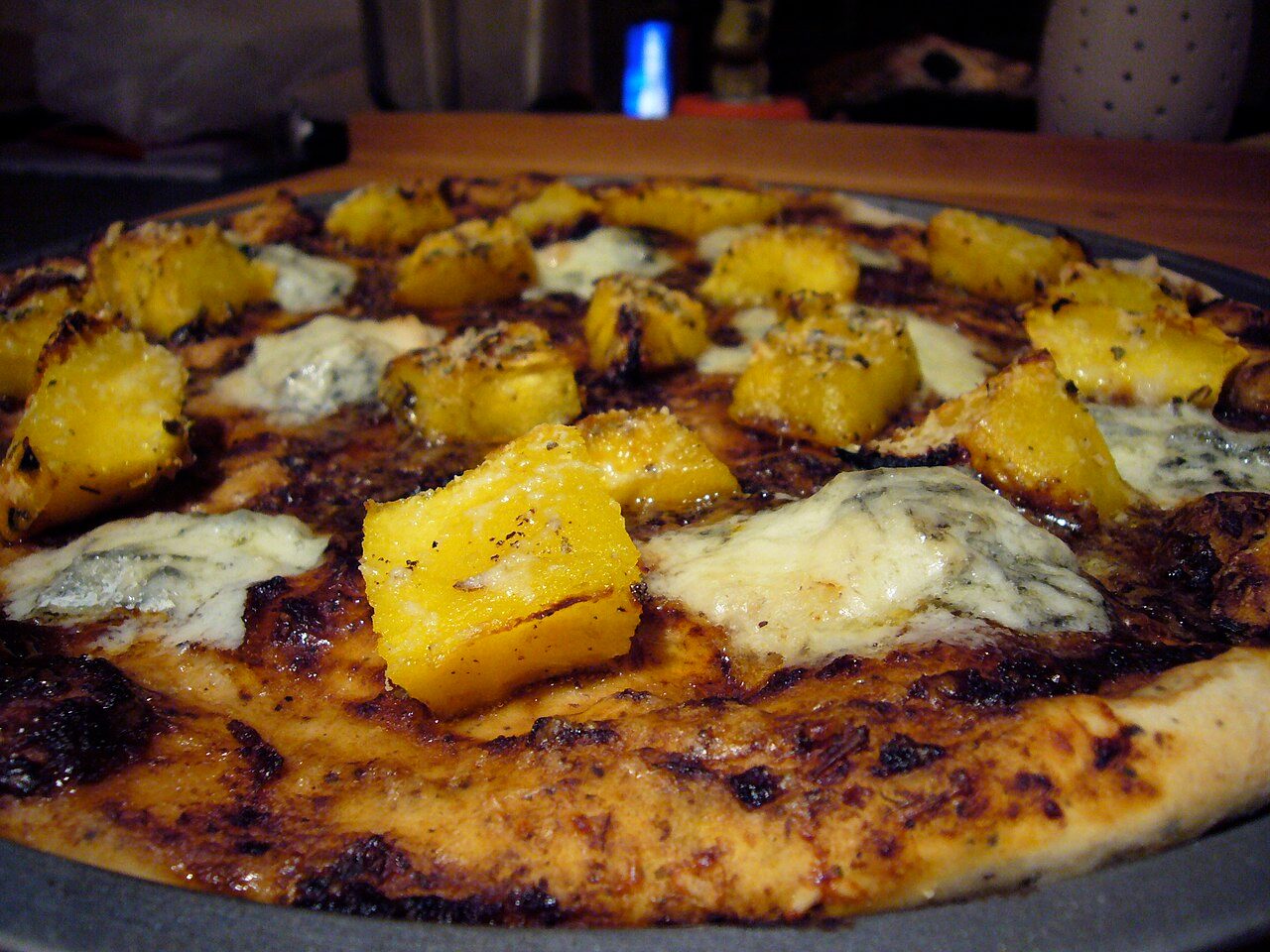 Pizza topped with acorn squash and gorgonzola cheese.