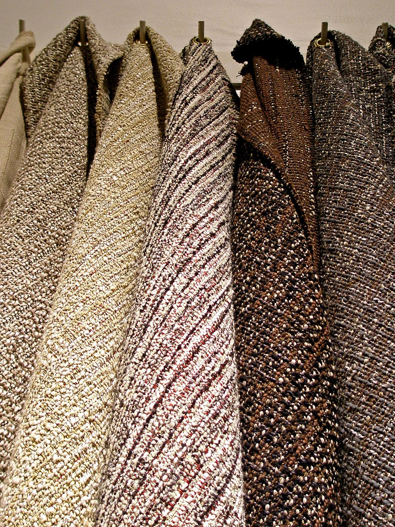 Tweed fabric hanging from hooks.