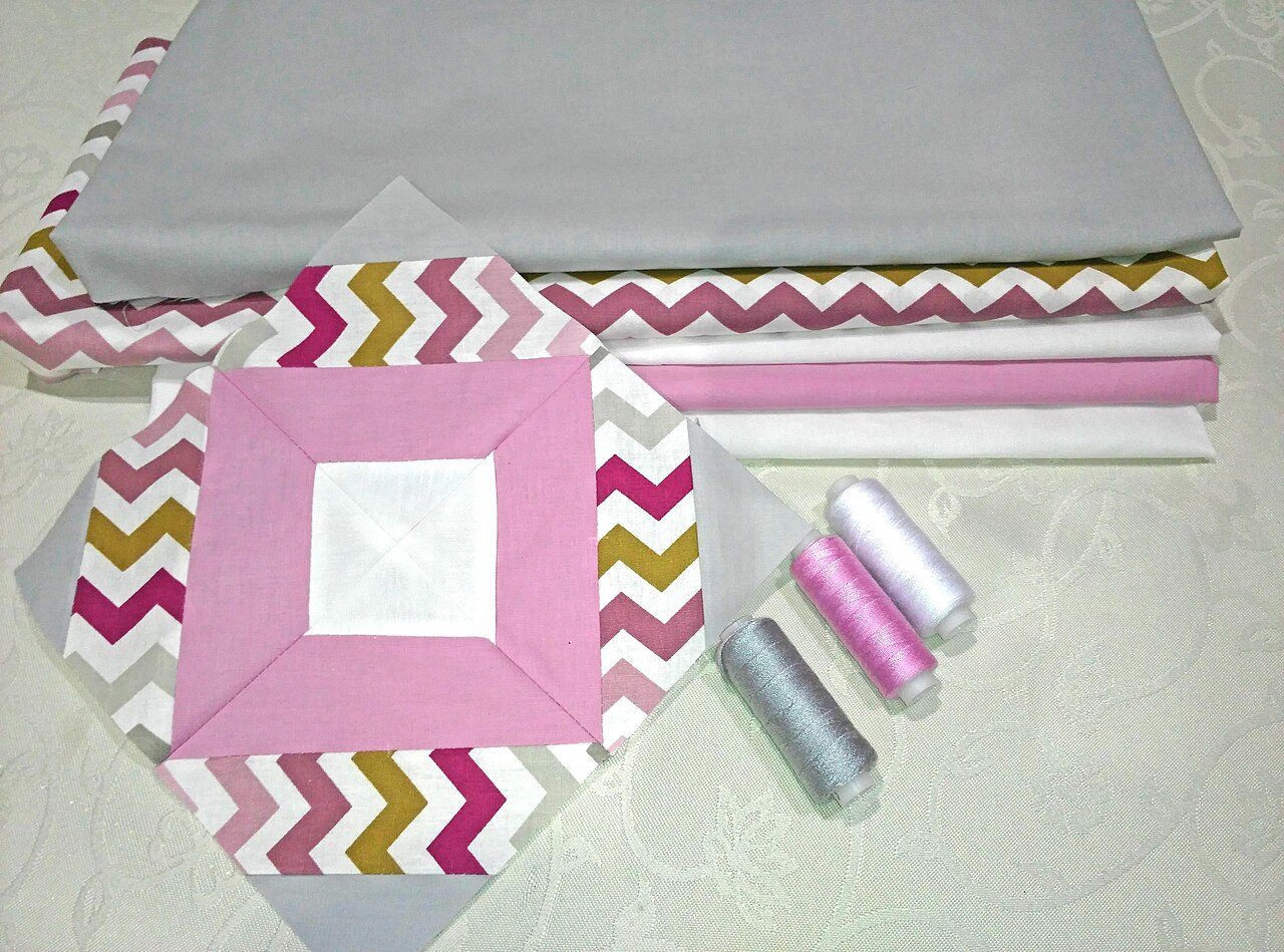 Quilt block shown in front of quilting fabrics and thread - originally taken for https://hellosewing.com/faq-tips-deal-quilting-issues/
