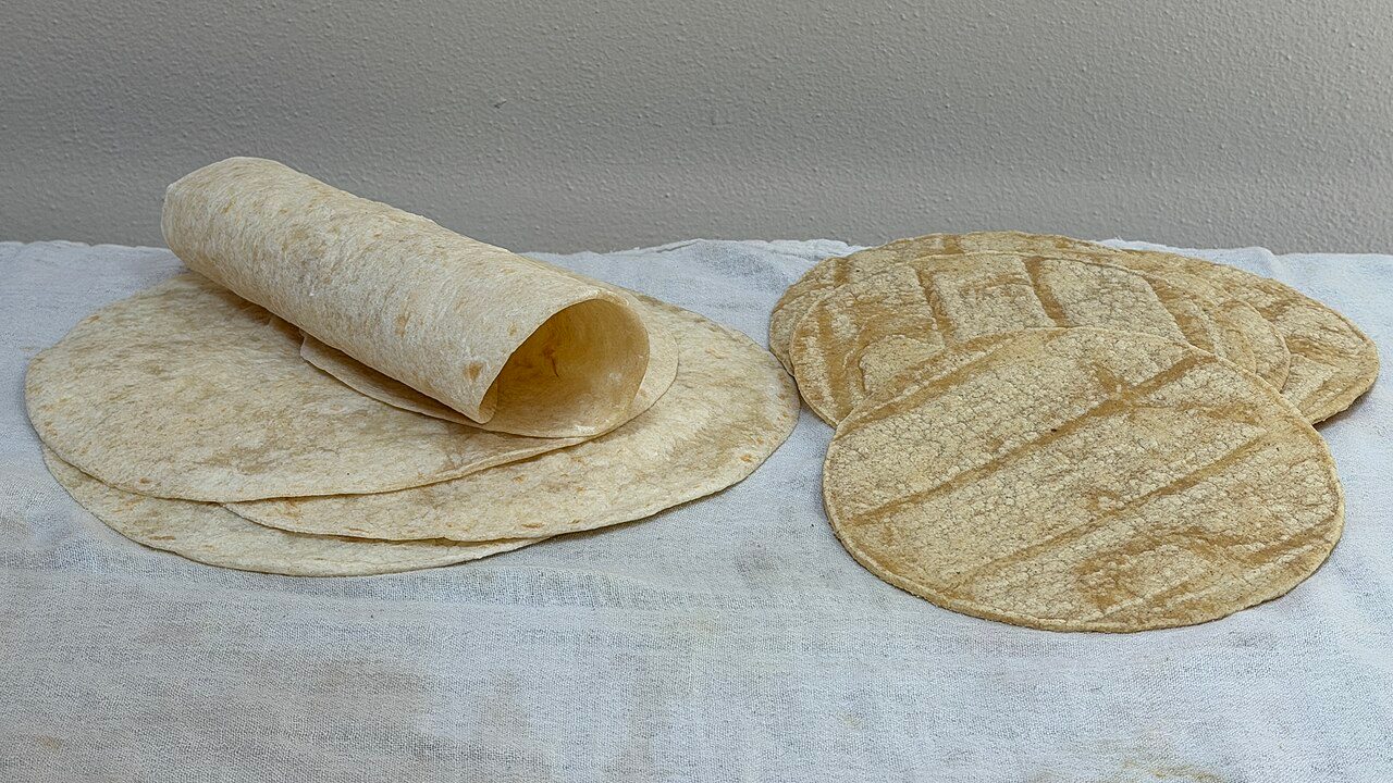A stack of flour tortillas (left) and a stack of corn tortillas (right). These tortillas were purchased from a local Hispanic grocery store slash tortillería.