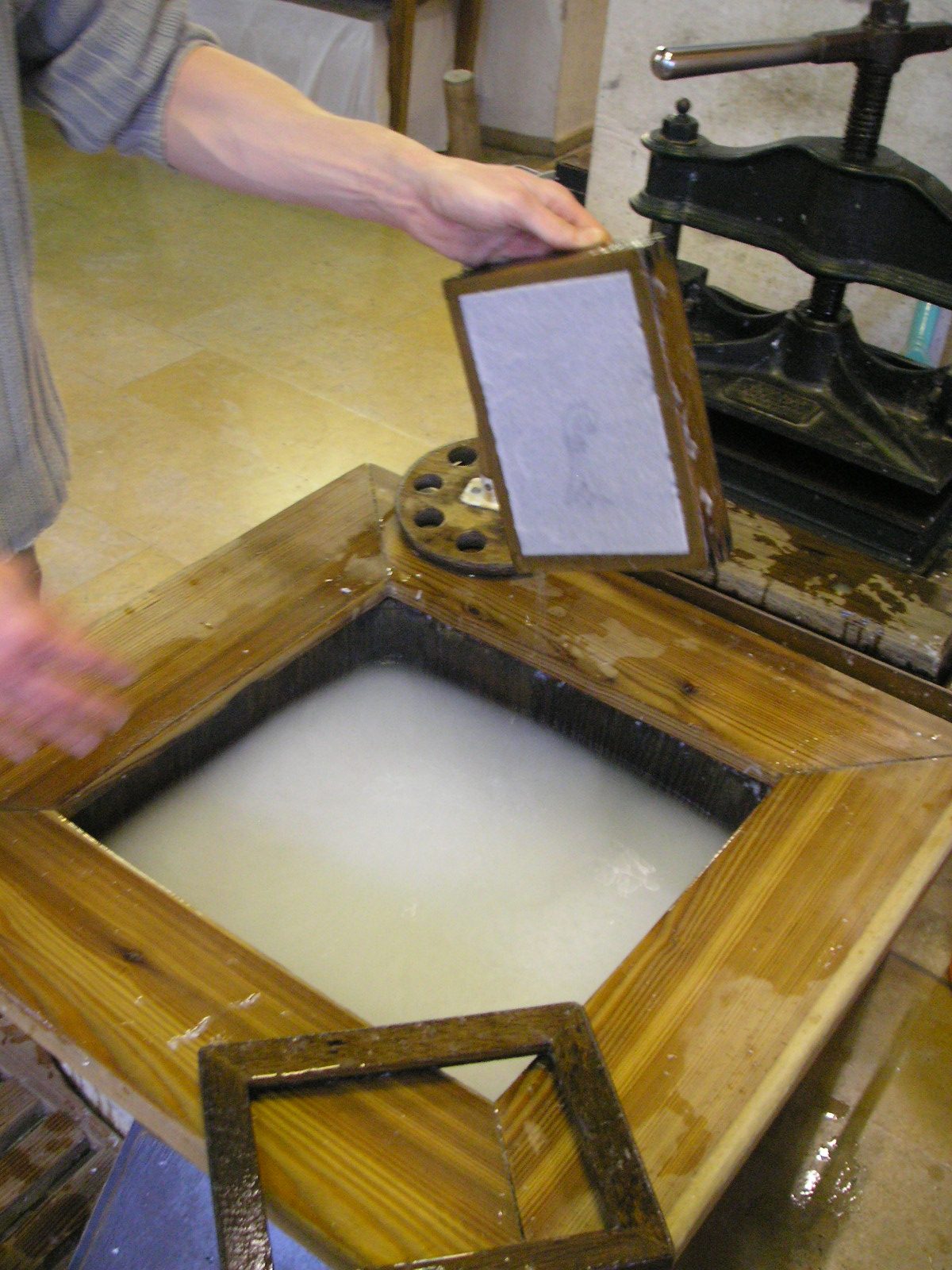 The production of hand-made paper. The pulp accumulates in the wooden-framed screen which is carefully taken out so that the pulp settles equally on all sides. The wooden frame is removed. The water drips away from the screen until the pulp sticks safely to it. With a swift…