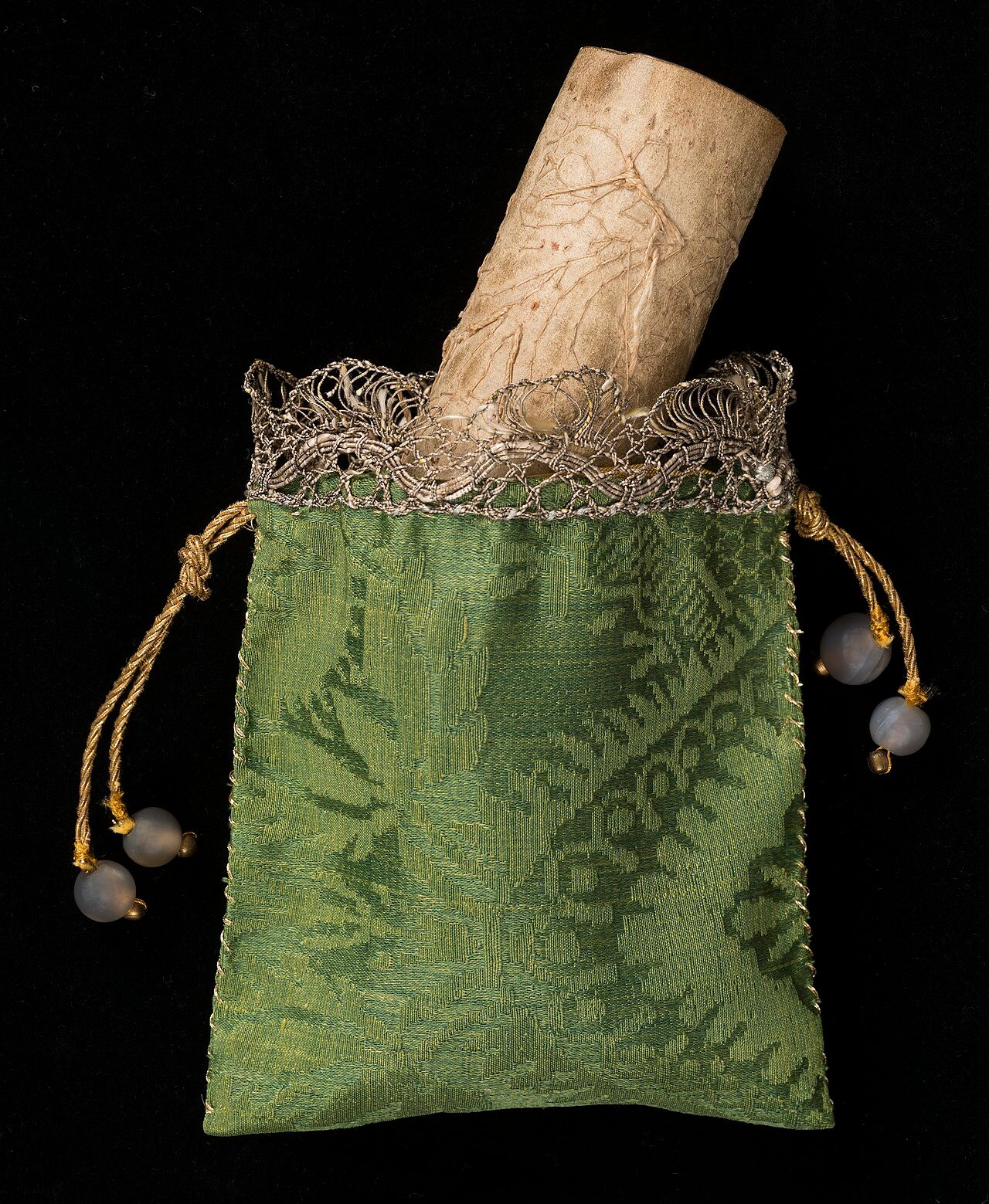 Long strip of parchment with design drawn onto it in ink. The outline of the design has been sewn onto the parchment with linen thread and about half of the needlelace has been filled in.The design is of curving floral sprays. There is no repeat in the width but it appears as if…