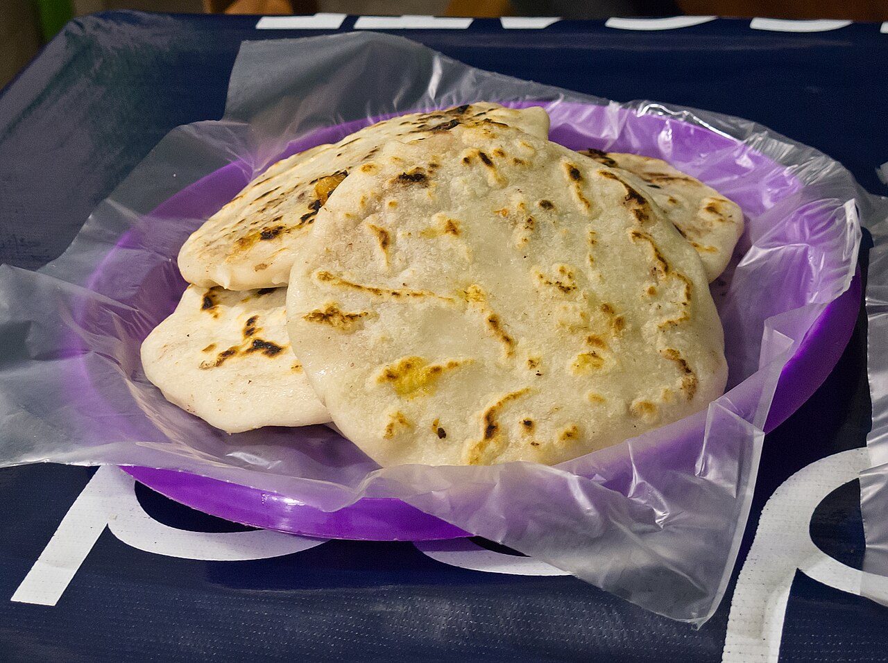 Pupusas, made in Olocuilta, La Paz, El Salvador. Note the way they are served here for an individual person is typical of pupuserias en El Salvador, i.e. plastic sheet over a round plastic tray.